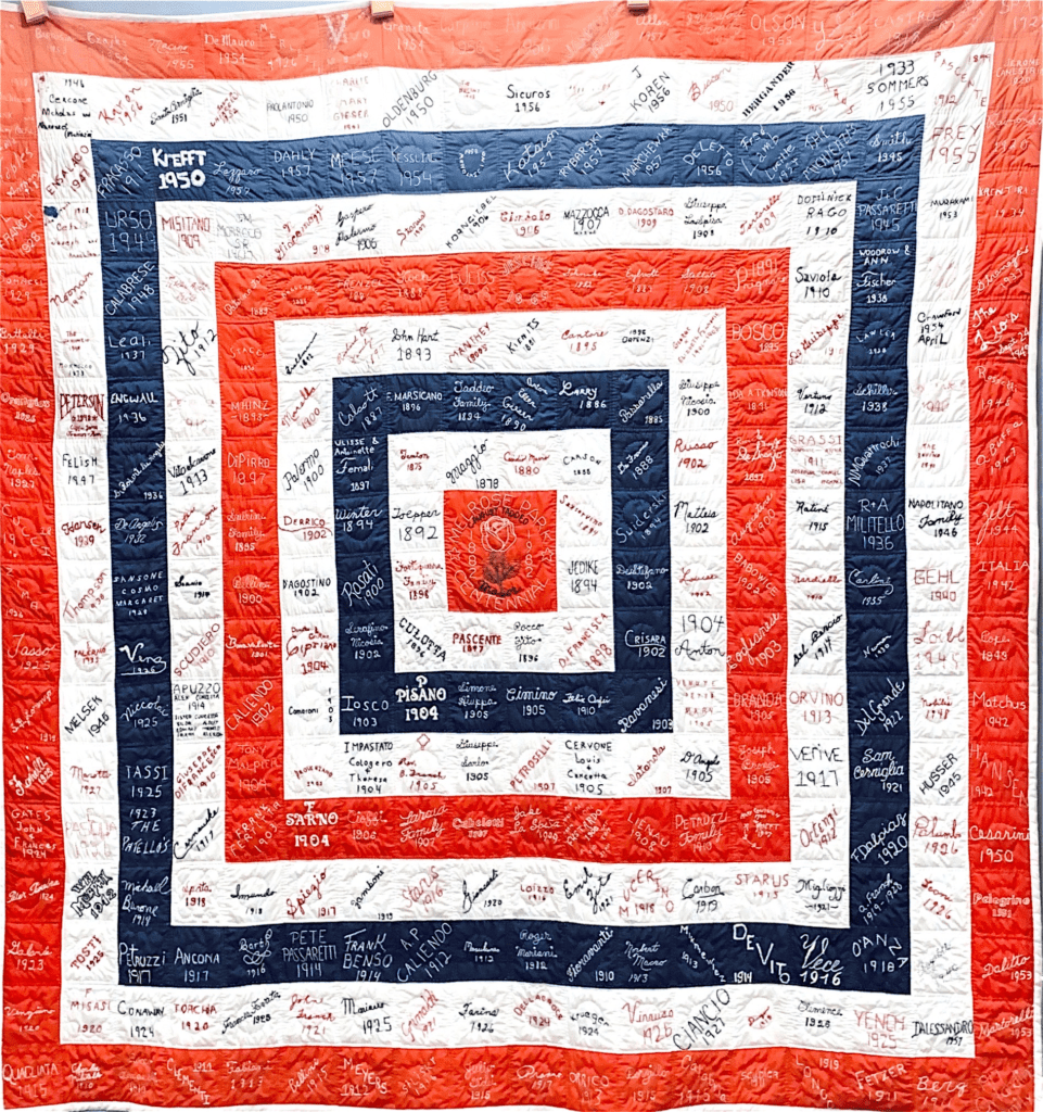 A square quilt with concentric rings of red, white, and blue fabric blocks, each covered in handwritten signatures.