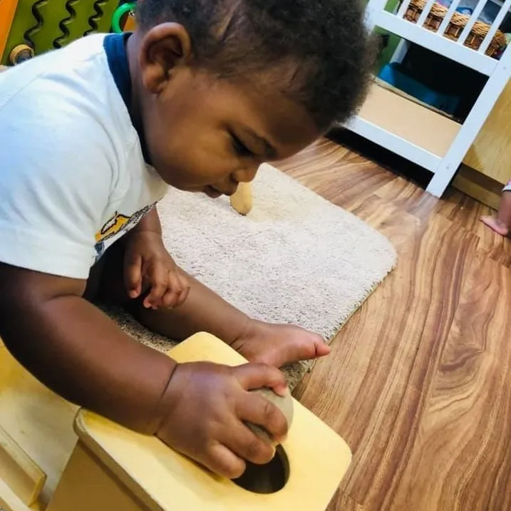 A little boy is playing with a wooden box on the floor