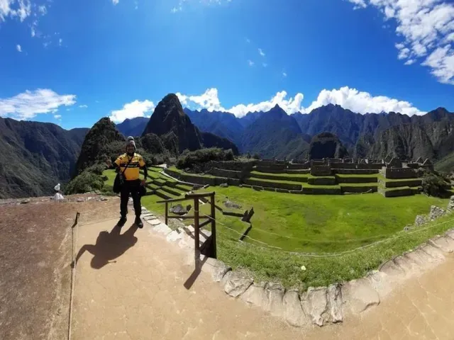 Excursionista con mochila amarilla en un sendero de piedra con vistas a las ruinas de Machu Picchu