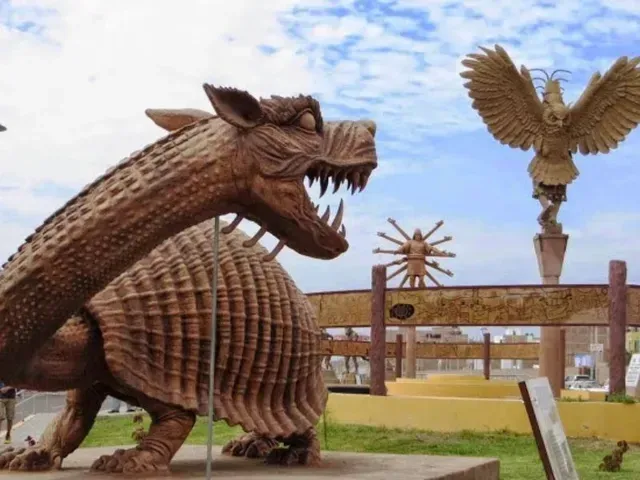 Gran escultura de madera de un armadillo al aire libre con una estatua de un águila y un molino de viento