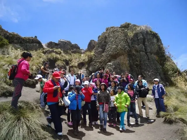 Grupo de excursionistas posando en un sendero rocoso de montaña bajo un cielo azul.