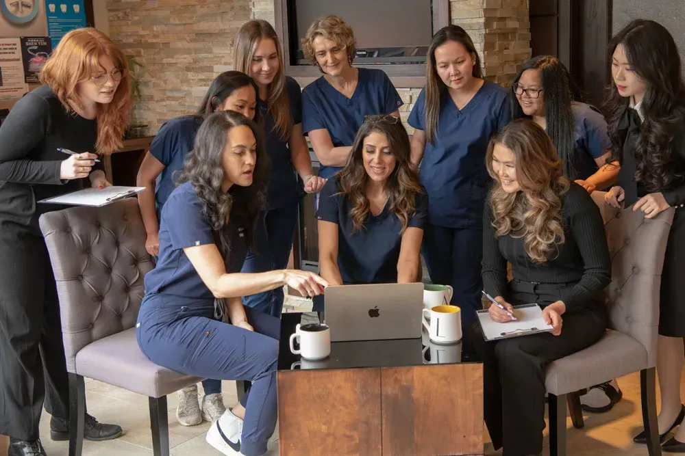 Group of women gathered around a laptop, looking at the screen and discussing.
