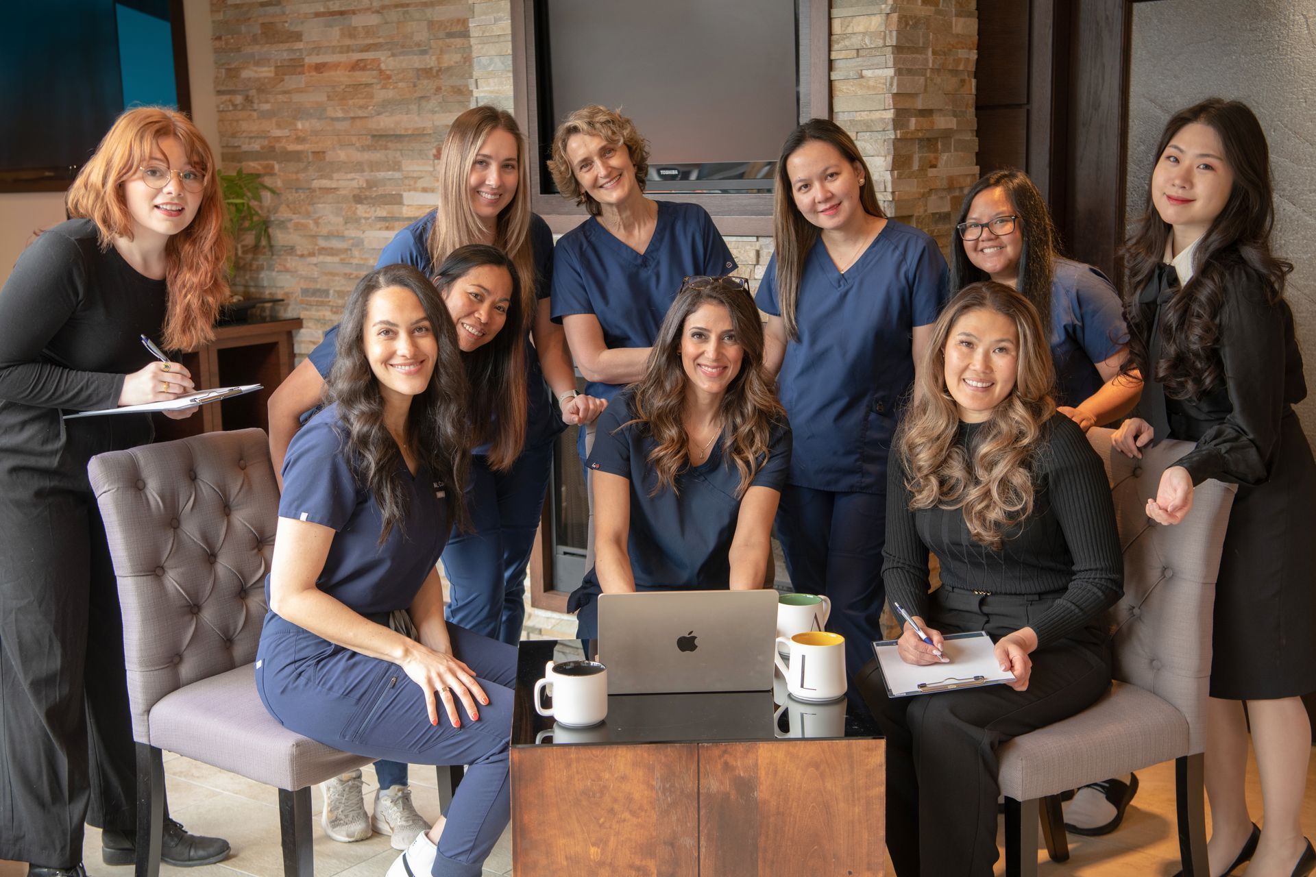 Group of colleagues smiling around a laptop in a cozy office lounge