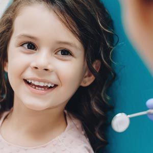 Smiling child blowing bubbles against a blue background