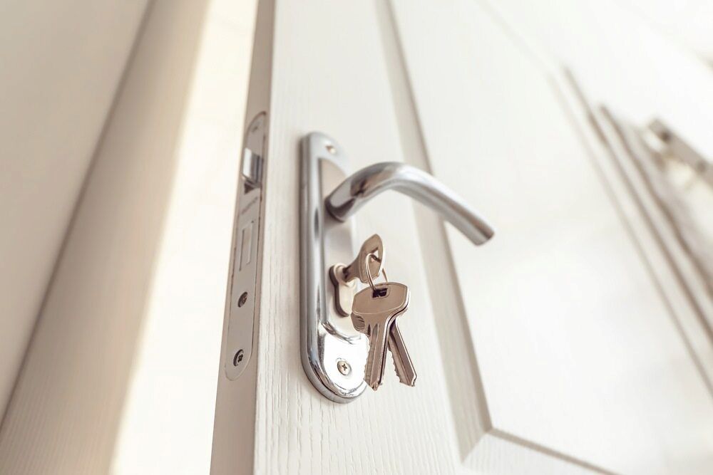 Keys Hanging From a Silver Door Handle on a White Door — Coast 2 Coast Locksmiths in Aura, QLD