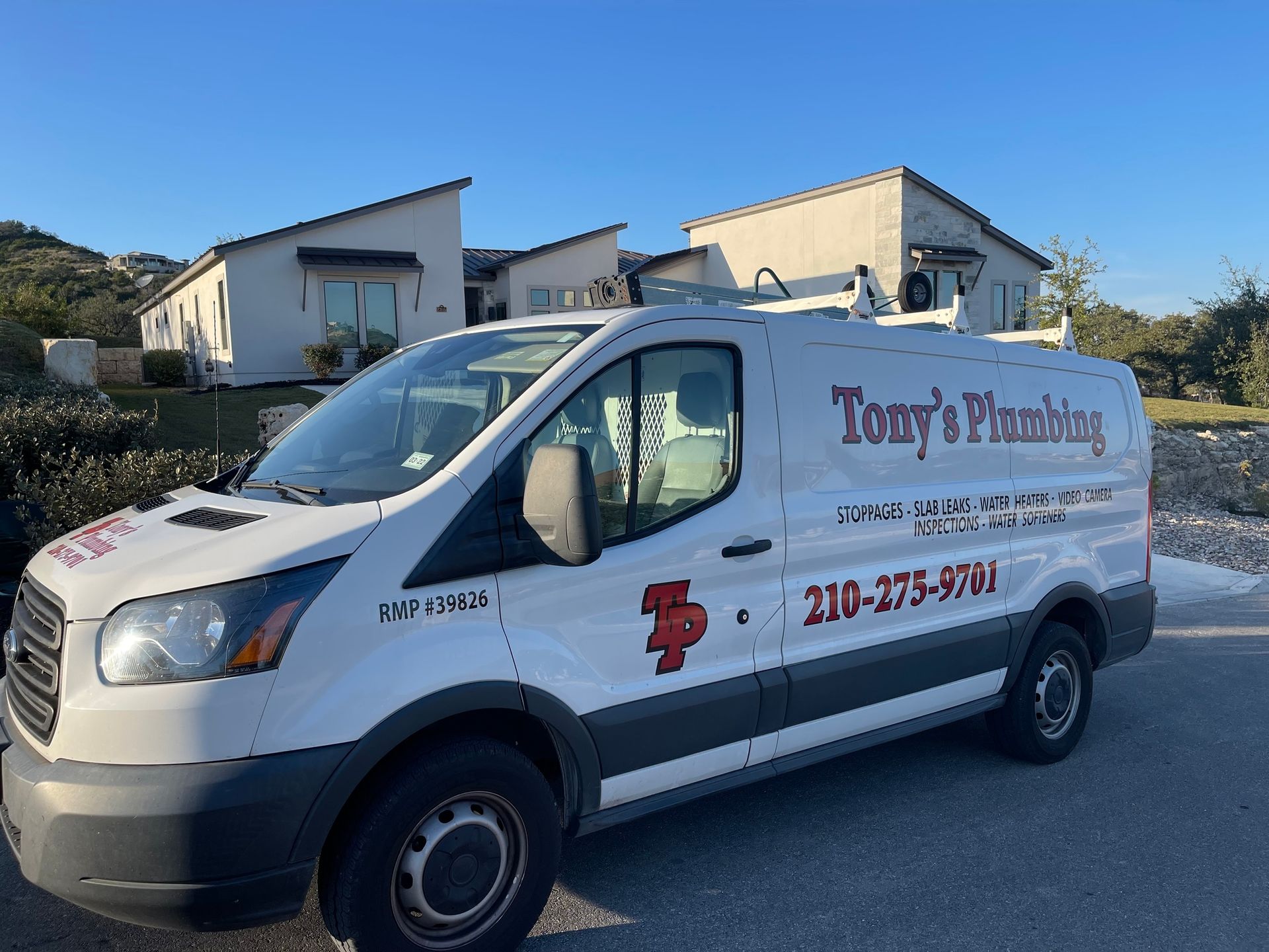 A tony 's plumbing van is parked in front of a house.