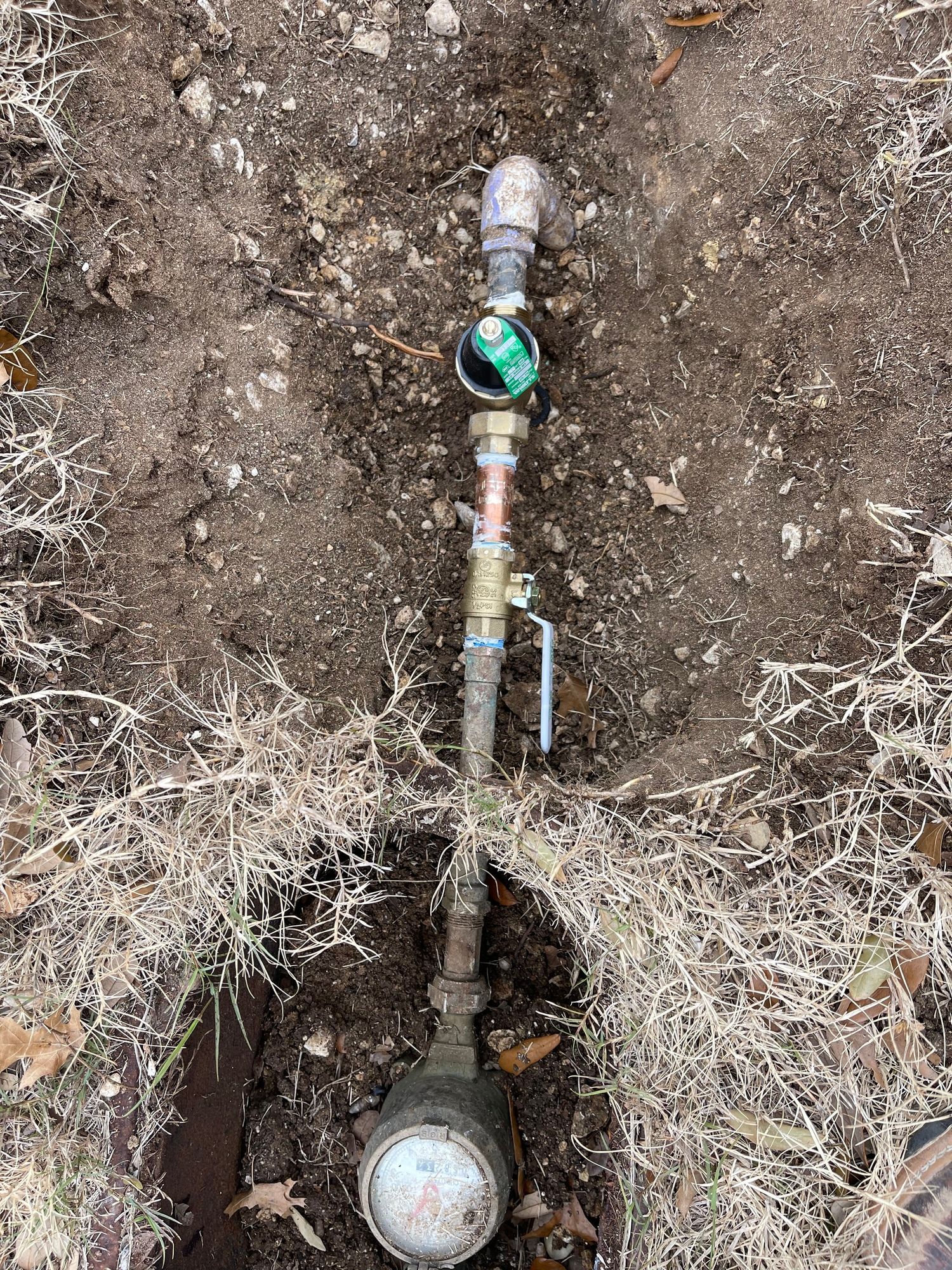 A water meter is sitting in the dirt in the ground.