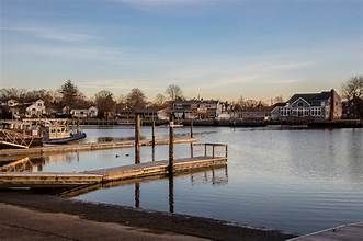Calm harbor with docks, moored boats, and waterfront houses under a clear sky