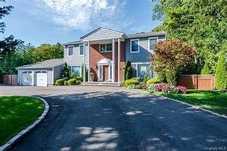 Large two-story suburban house with a driveway, garage, and landscaped front yard.