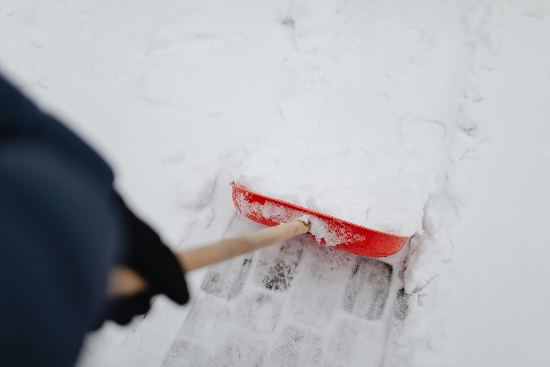 A person shoveling snow with a red shovel
