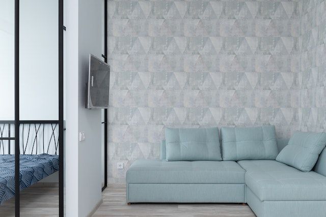 Interior of apartment with a bedrrom, a green couch, and wallpaper on the walls