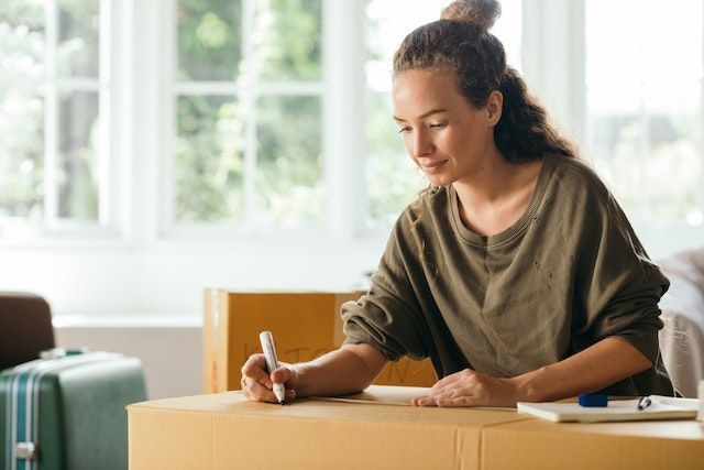 Person sitting and labelling a moving box