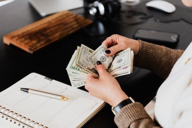 Person sitting at their desk counting twenty dollar bills