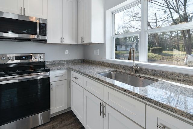Wide shot of kitchen with an oven, countertops, cabinets, and a wide window