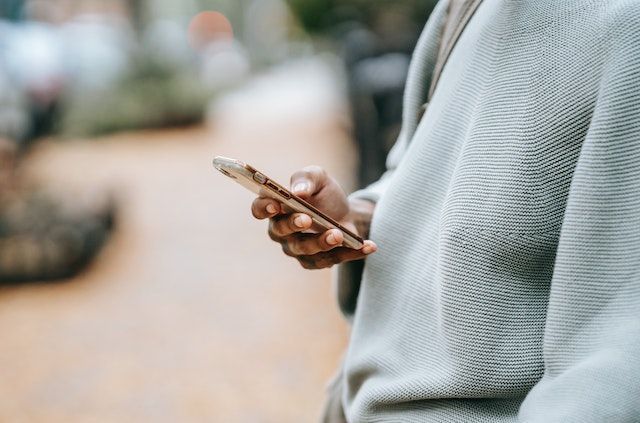 Cropped person in a gray sweater holding a phone
