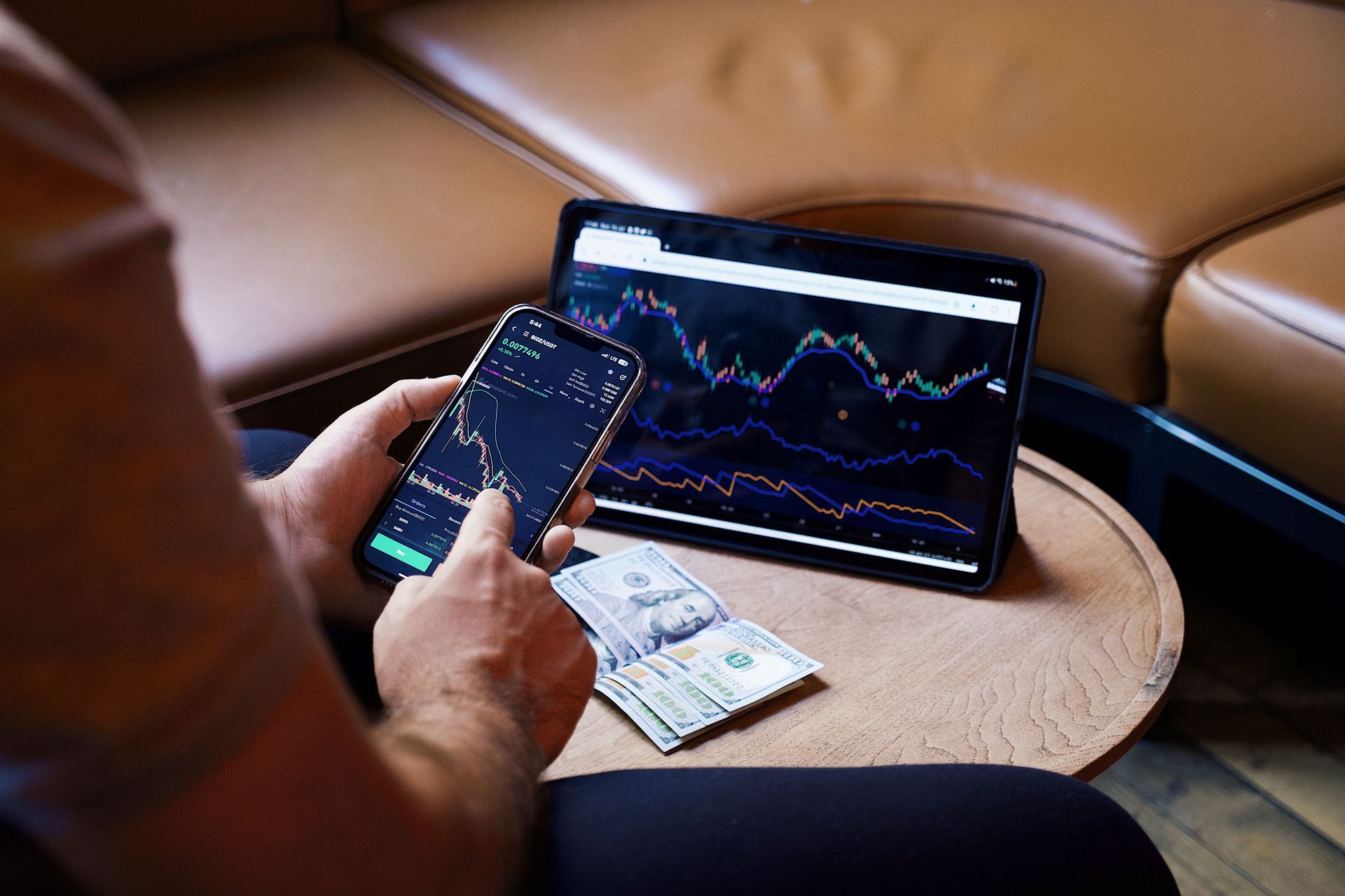 person using a smartphone and tablet for stock market analysis