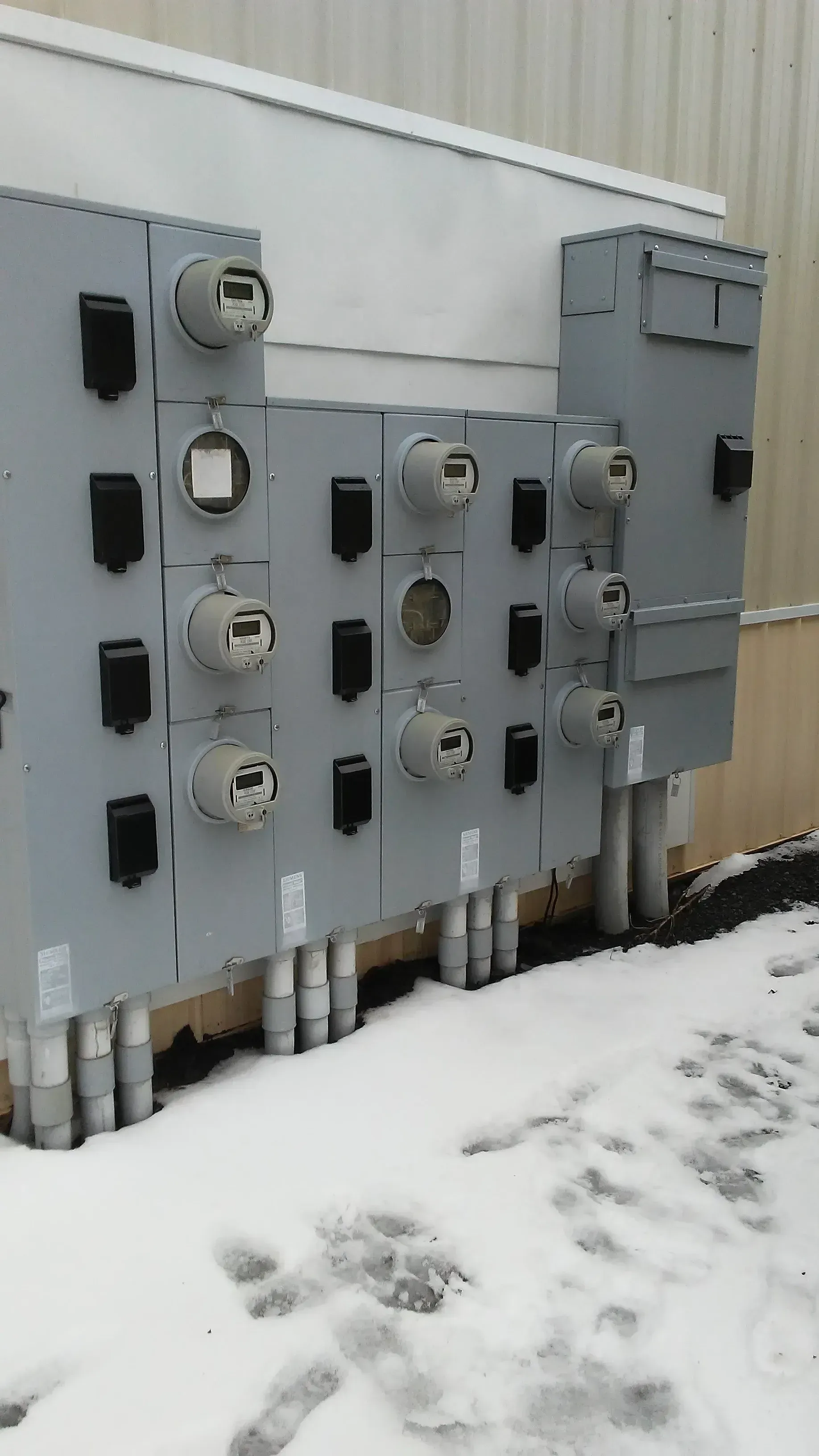 Snow-covered electrical utility panels mounted on a building exterior