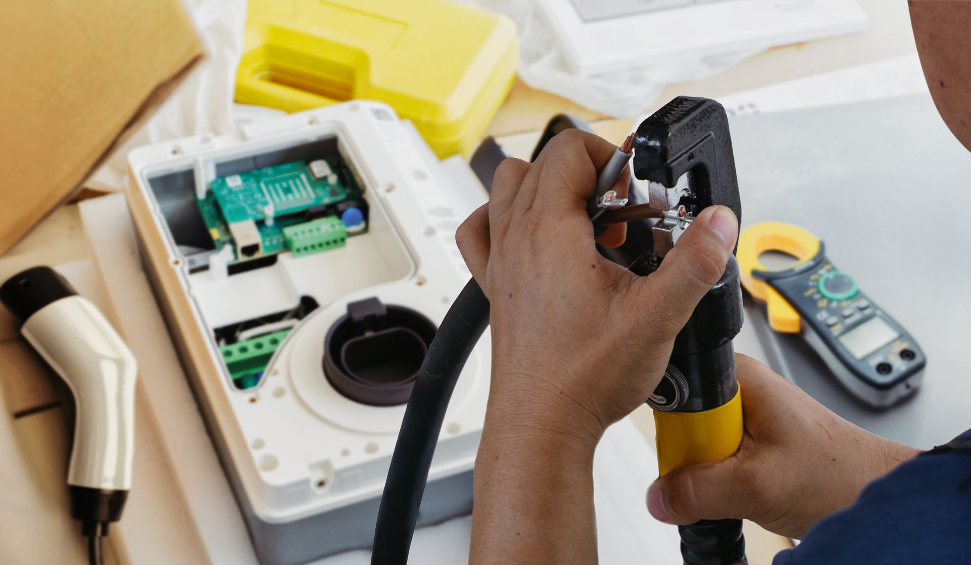 Hands repairing a yellow-and-white appliance with tools and exposed internal parts on a workbench