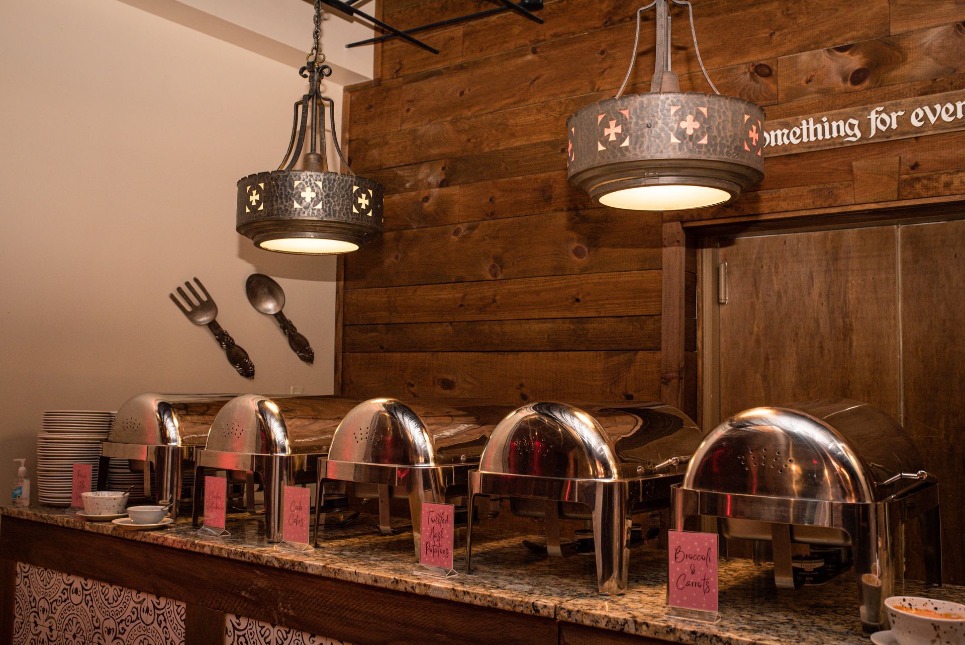 A buffet line in a restaurant with a wooden wall behind it.