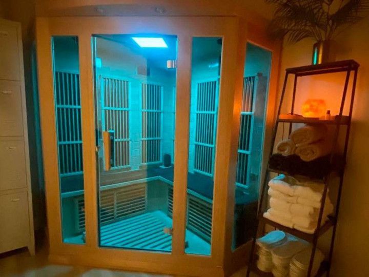 Outdoor sauna with glass doors and blue lighting beside a towel shelf