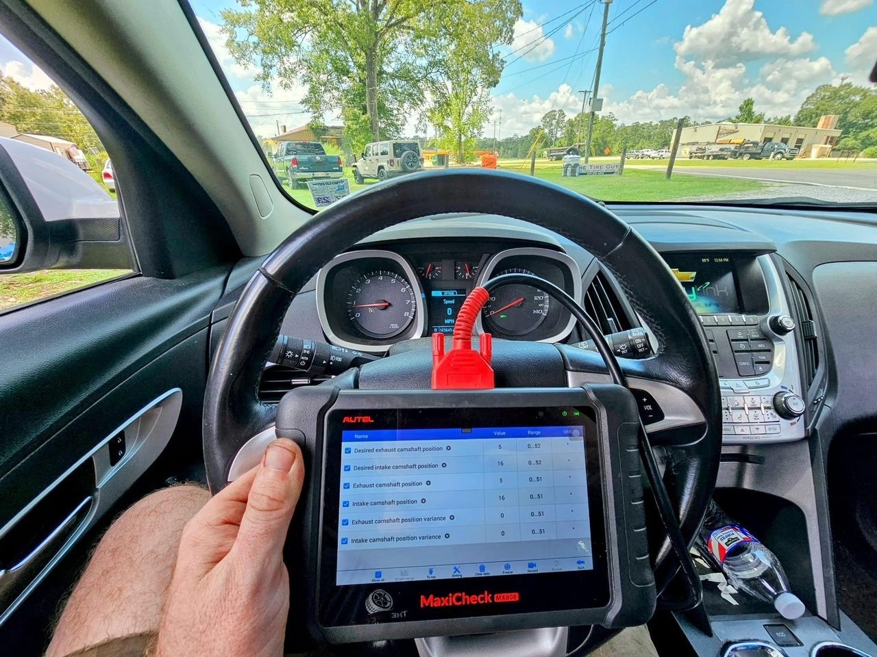 A person is sitting in a car using a diagnostic device.