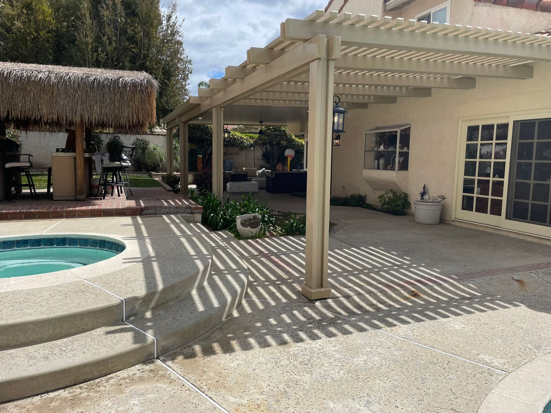 Poolside patio with a pergola, a tiki bar, and a pool.