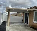 Covered patio with a concrete floor, lights, and a ceiling fan next to a house with sliding glass doors.