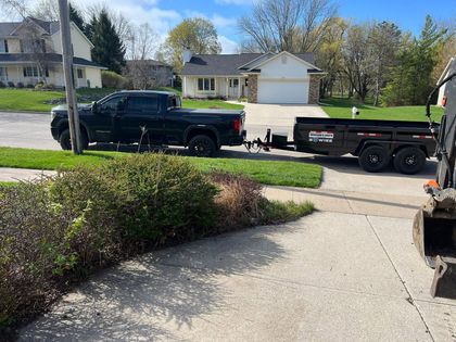 Black pickup truck towing a black trailer parked on a suburban street in front of a house