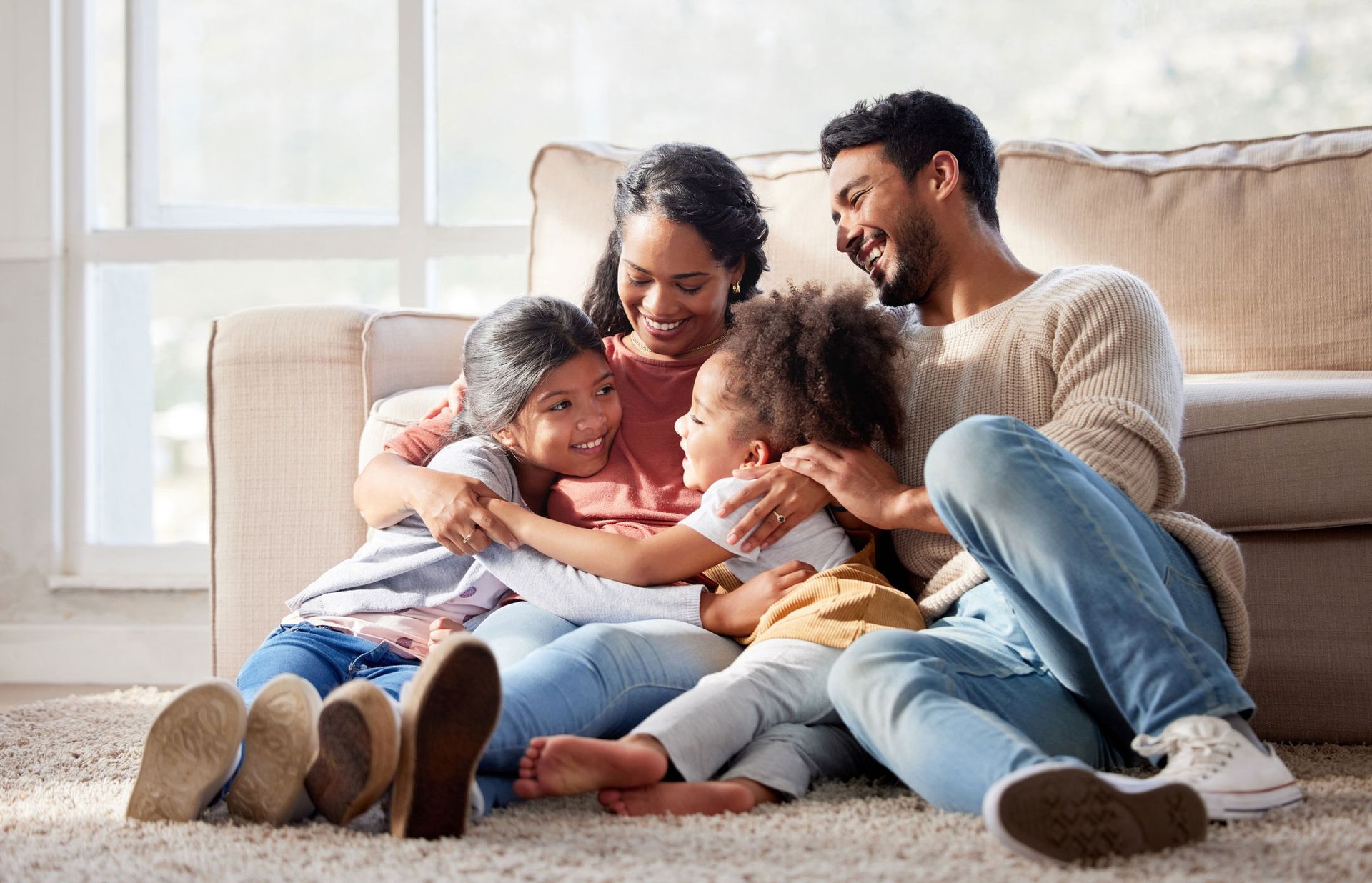 A family is sitting on the floor in front of a couch.