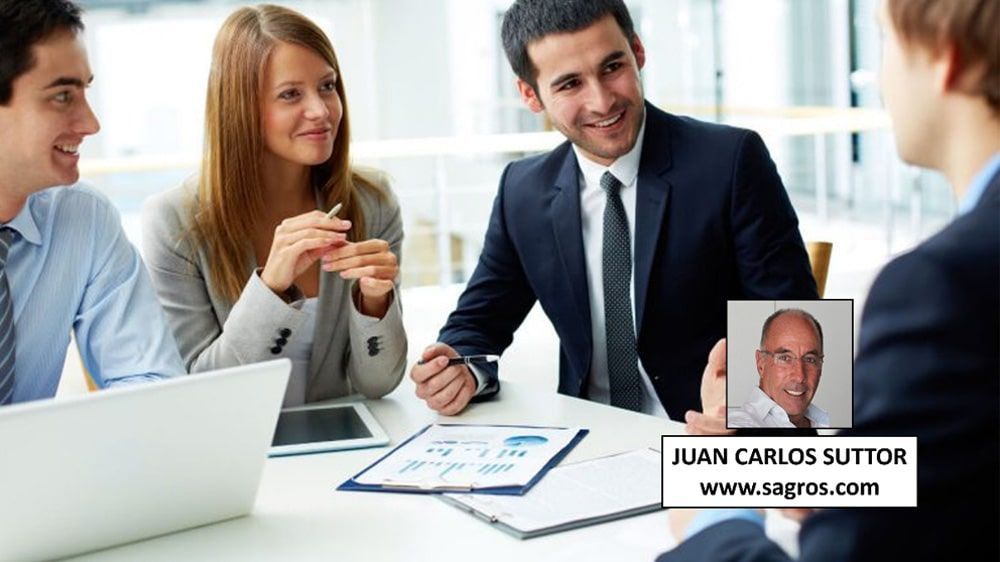 Un grupo de personas está sentado alrededor de una mesa con Juan Carlos Sutton en primer plano.