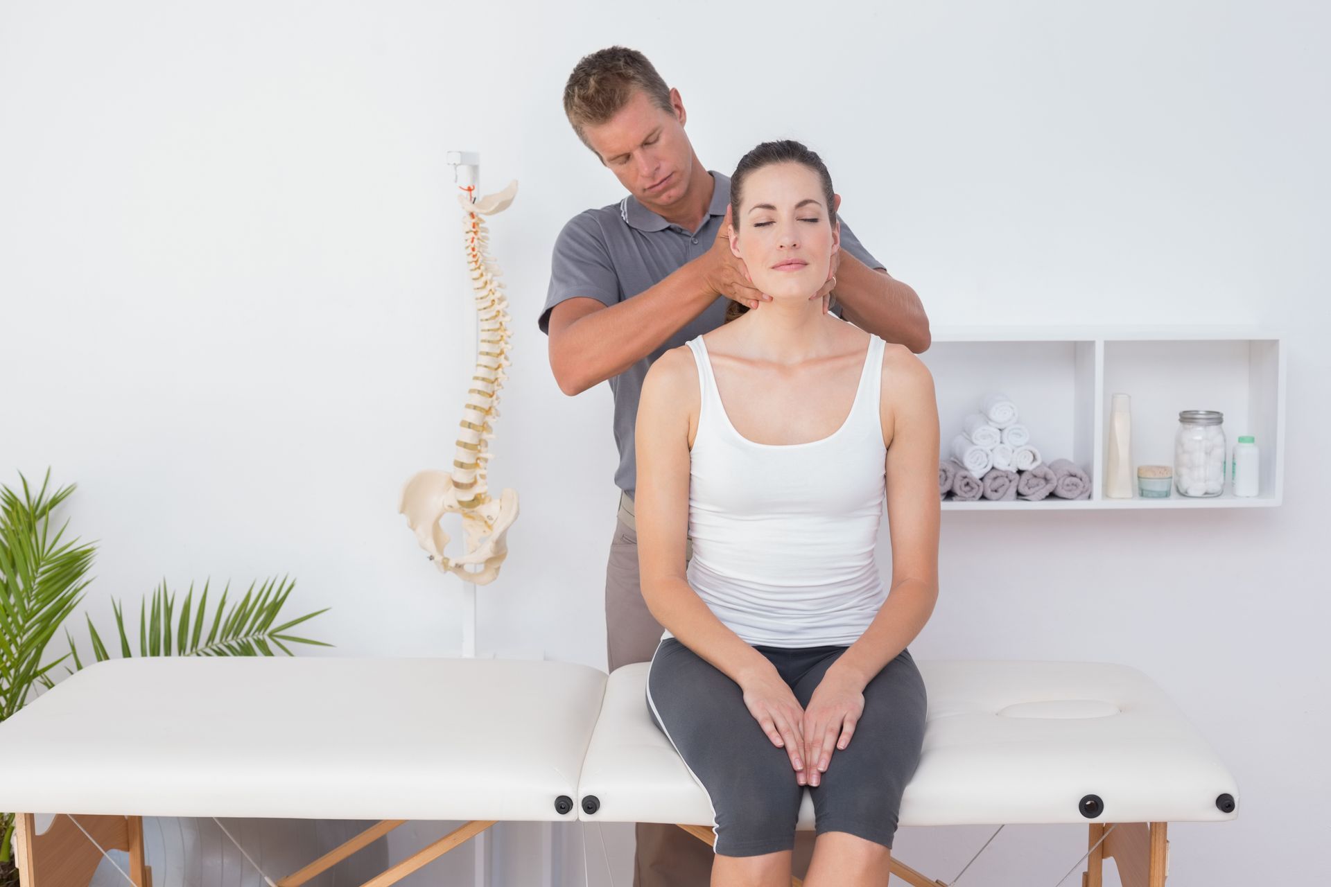 Chiropractor visit with a practitioner performing a neck adjustment on a patient in a treatment room