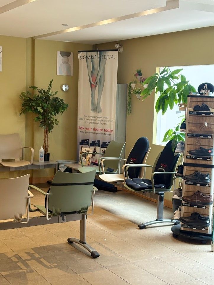 Dental clinic waiting area with chairs, plants, and a poster banner by the window.