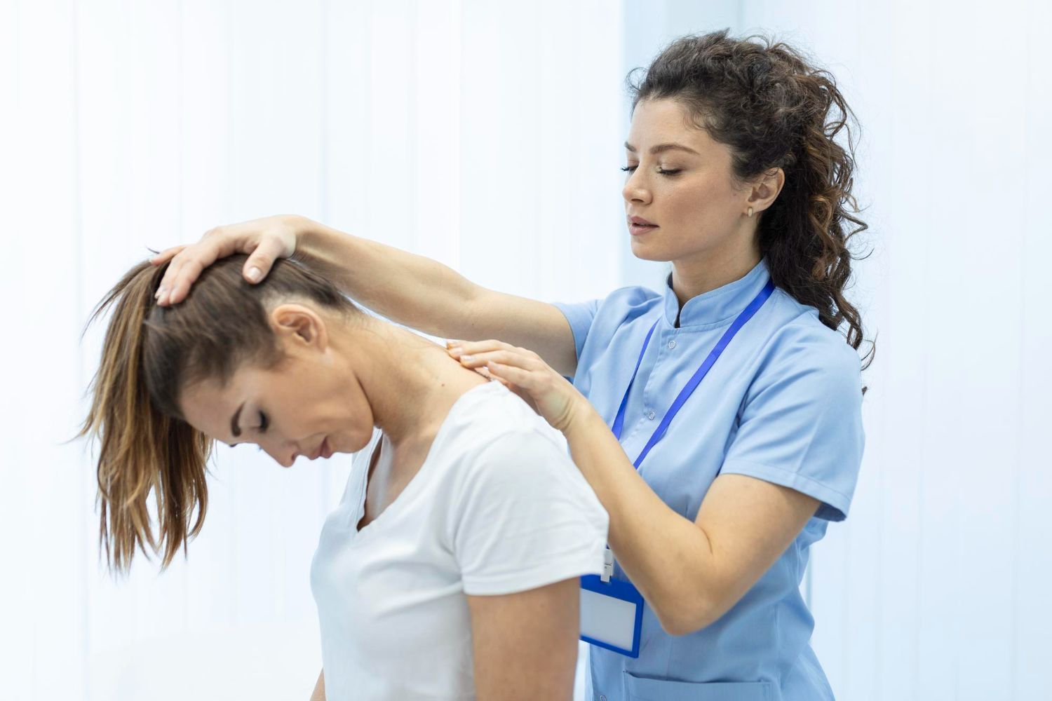 Physical therapist supporting a patient’s neck and shoulder during treatment in a bright clinic