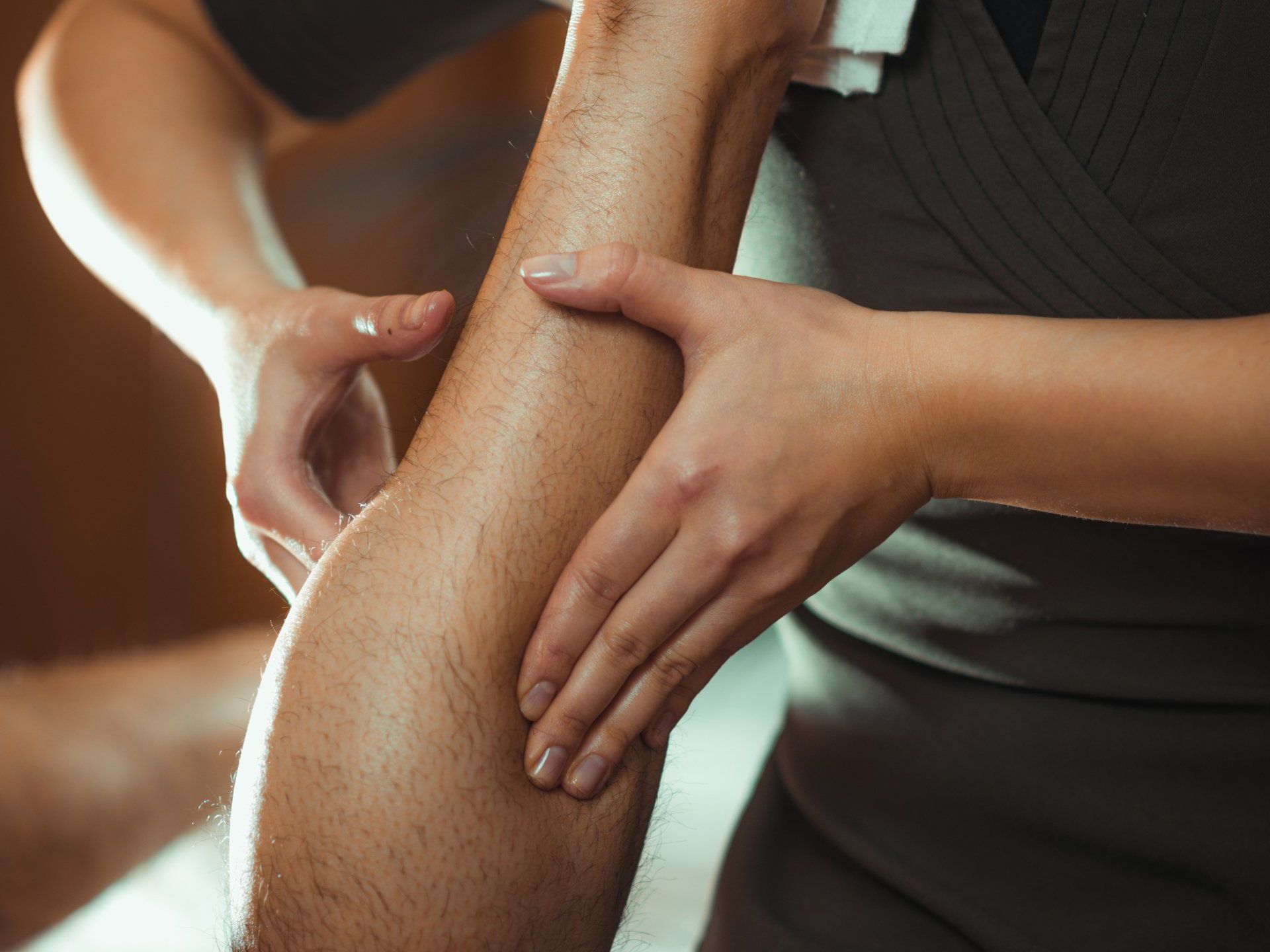 A woman is giving a man a massage on his leg.
