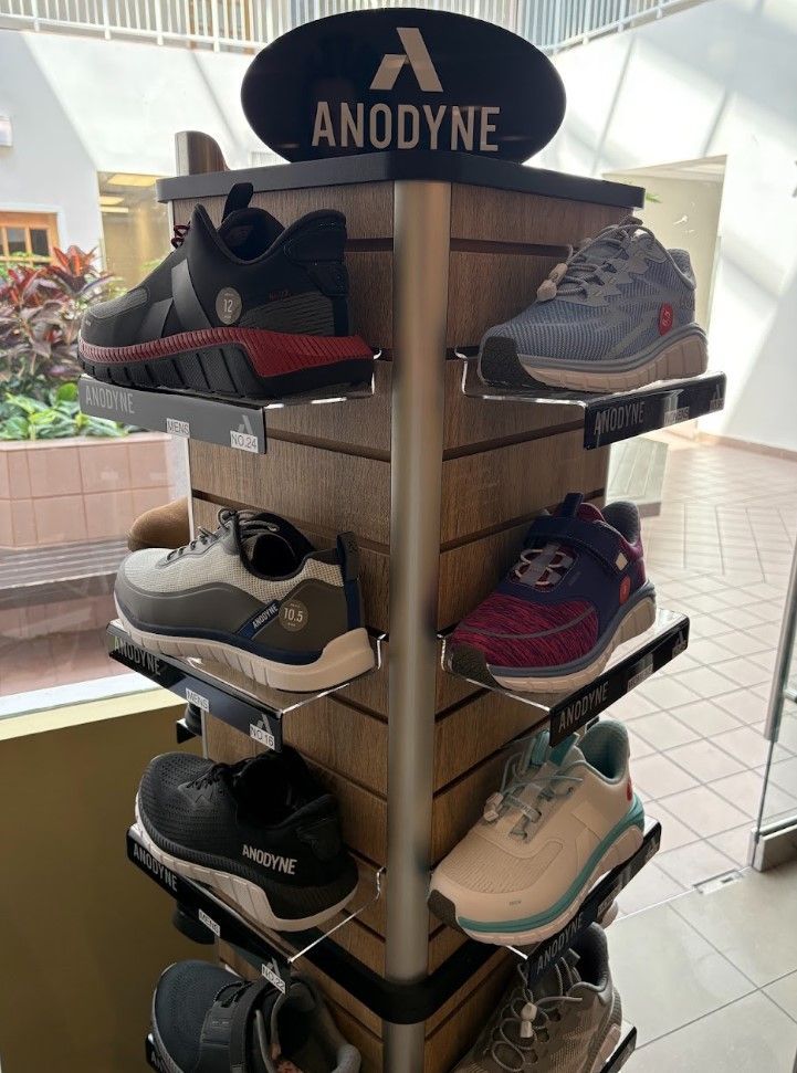 Shoe display rack with Anodyne-branded athletic shoes in a store, showing multiple sneaker styles.