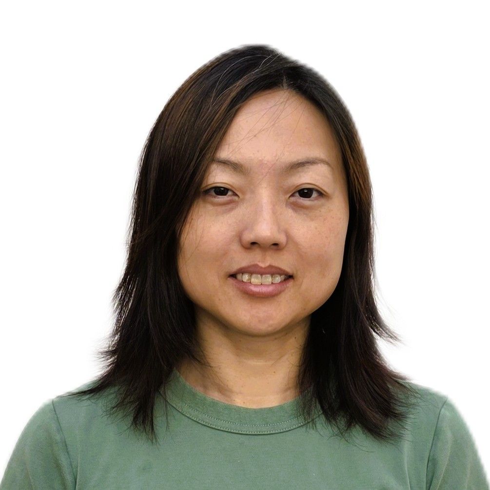 Portrait of a person with shoulder-length dark hair wearing a green shirt against a white background