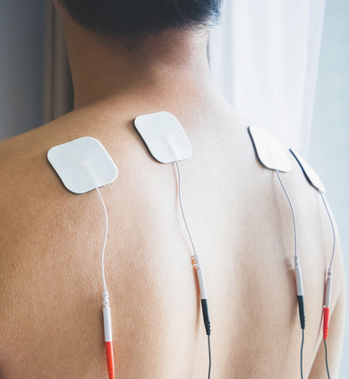 Back view of a person wearing four white electrode pads on the upper back with wires attached