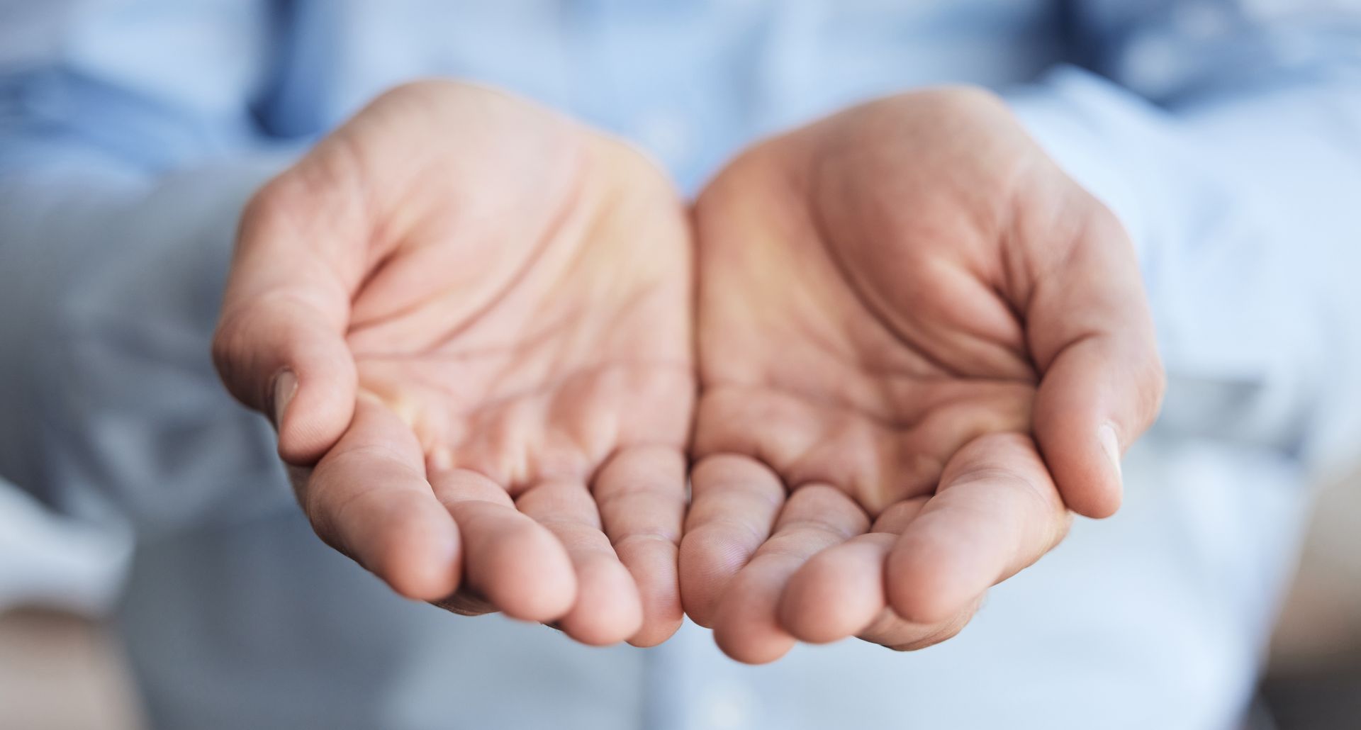 Two open hands cupped together, palms up, against a blurred blue background