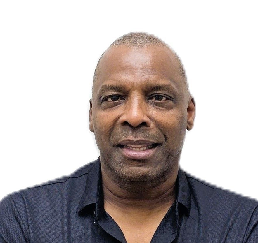 Portrait of a man in a dark shirt against a white background, facing forward and smiling slightly