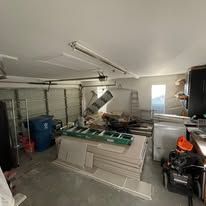 Damaged garage with a collapsed ceiling and debris, green workbench in the foreground.