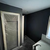 Small bathroom under renovation, with a plastic-covered door and dark gray walls.