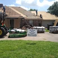 Roofing crew working on a house with materials and equipment in the driveway