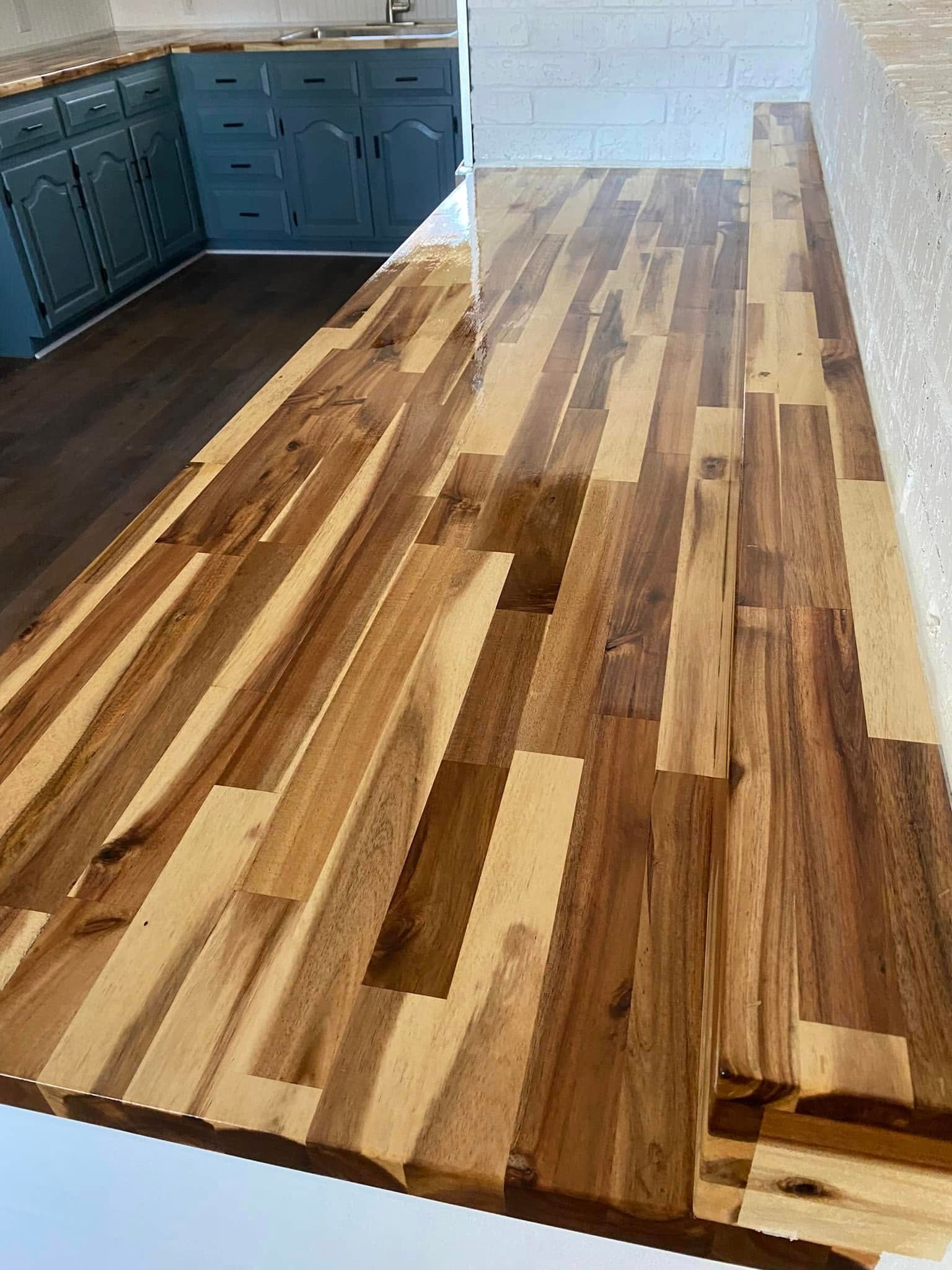 Partially finished kitchen floor with mixed wood planks beside blue cabinets