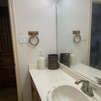 Bathroom vanity with sink, mirror, and countertop decor in a neutral-toned interior