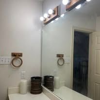 Bathroom vanity with mirror, light bulbs, towel ring, and toiletries on the counter