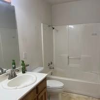 Bathroom with white vanity, sink, mirror, toilet, and bathtub with shower curtain.