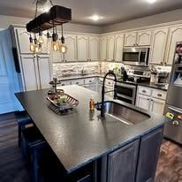 Modern kitchen with large island, stainless appliances, light cabinets, and pendant lights