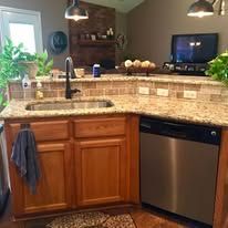 Kitchen with granite countertop, wood cabinets, stainless dishwasher, sink, and pendant lights above a breakfast bar