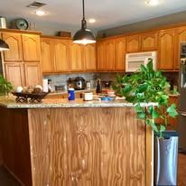Kitchen with wooden cabinets, granite island, and a large potted plant by the counter.