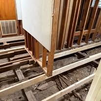 Exposed floor joists and framing in a stripped interior under renovation